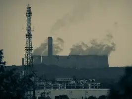 smoke billows from the stacks of industrial buildings