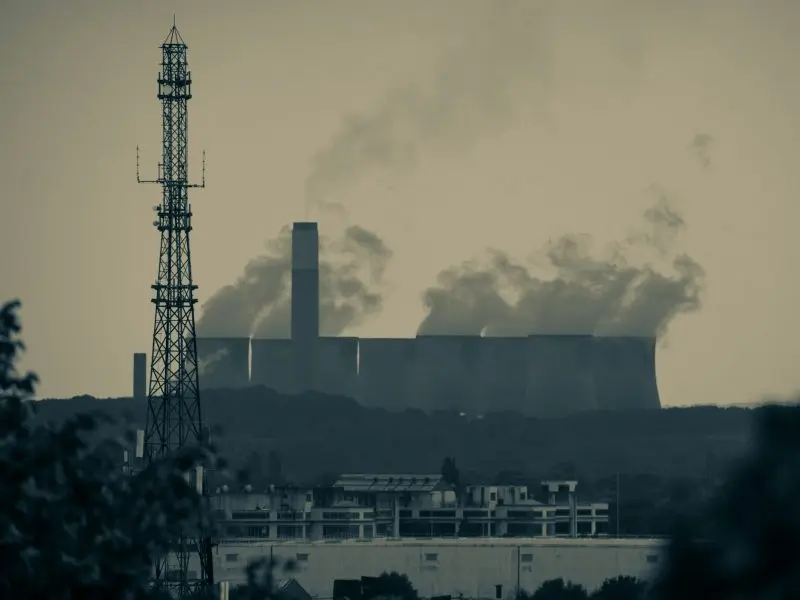 smoke billows from the stacks of industrial buildings