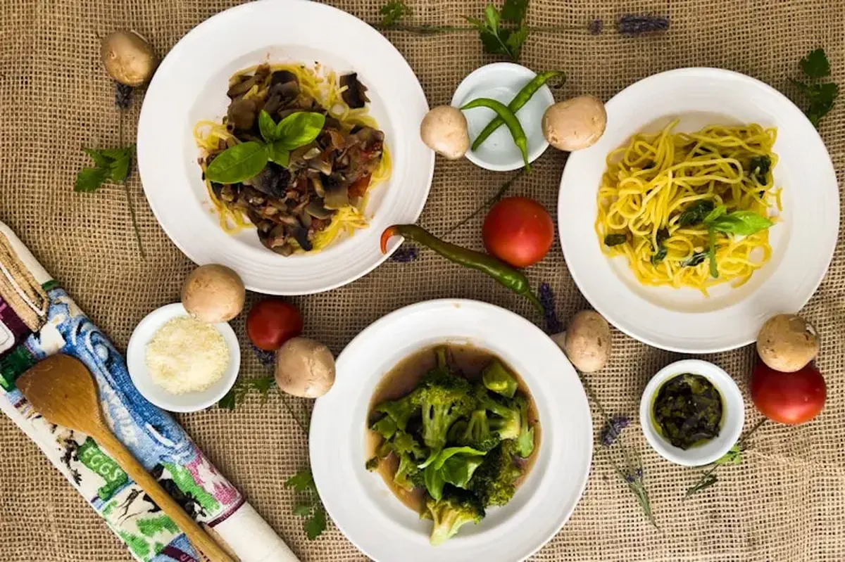 Pasta with green leafy vegetables in a white ceramic bowl.