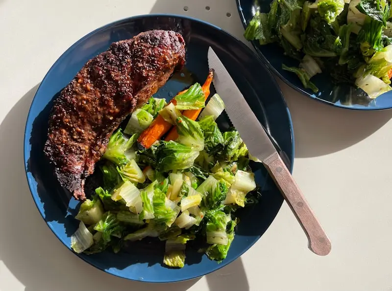 cooked meat with vegetables on a black plate