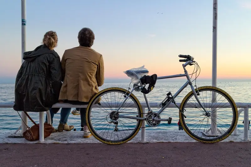 A man and woman sitting on a bench by the sea