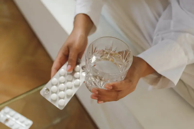 hands with pills and a glass of water
