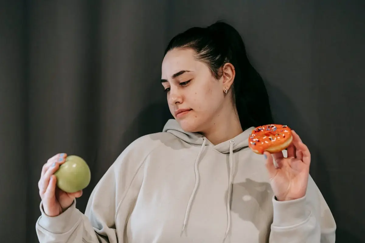 A girl chooses between an apple and a donut