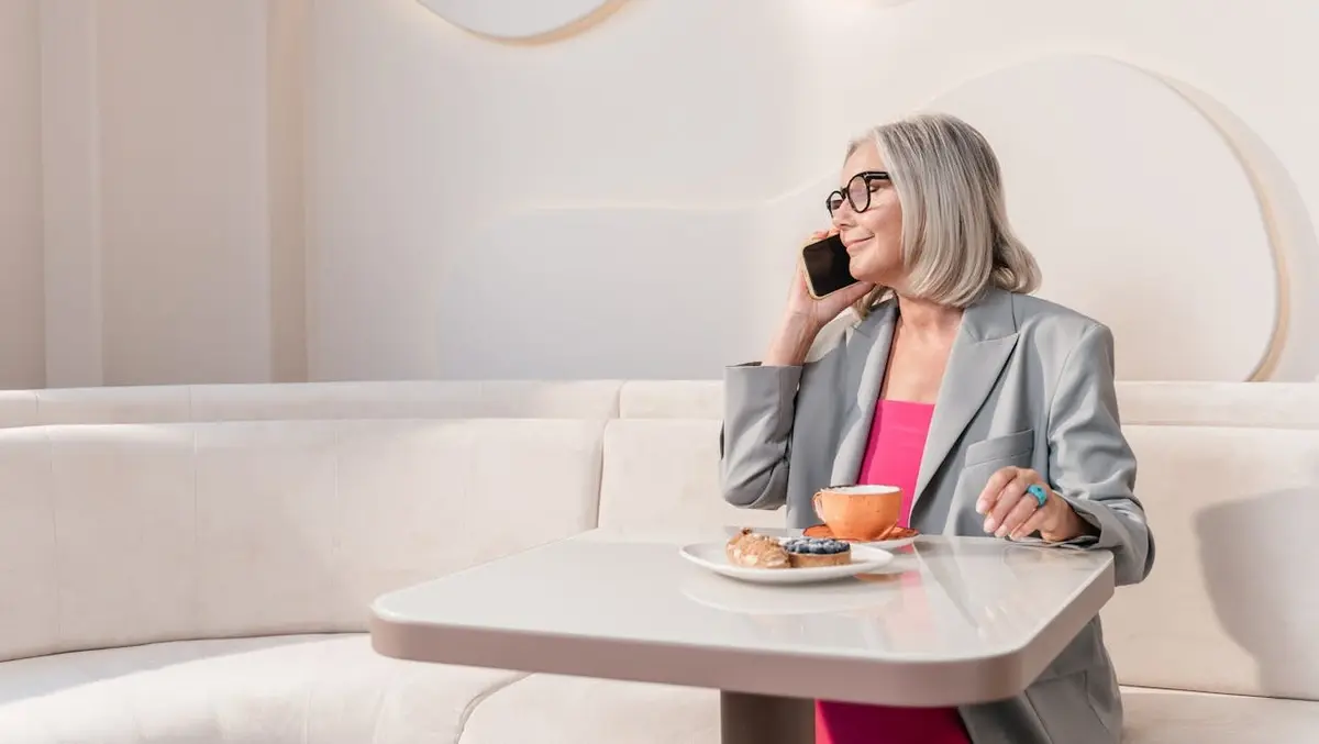 A woman at a table with food talking on the phone