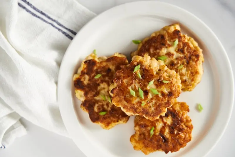 a white plate topped with crab cakes on top of a table