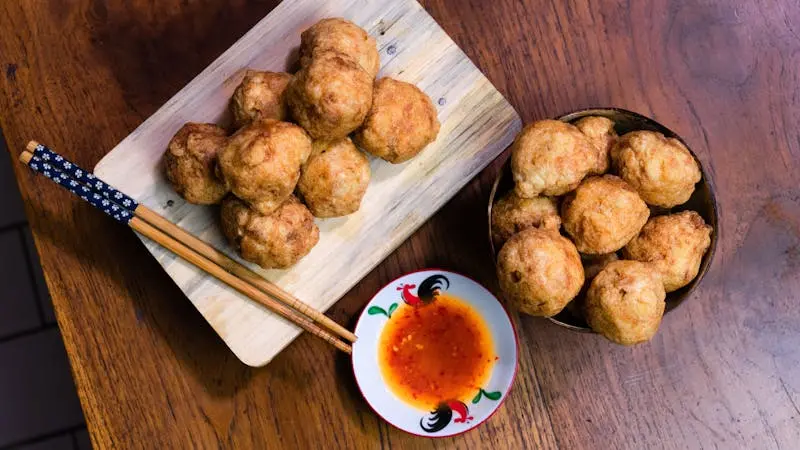 Delicious Indonesian fried snacks served with spicy dipping sauce on a wooden table.