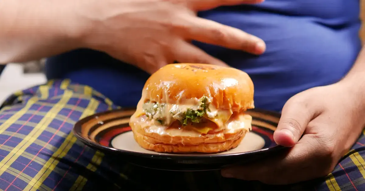 man with obesity holding a hamburger
