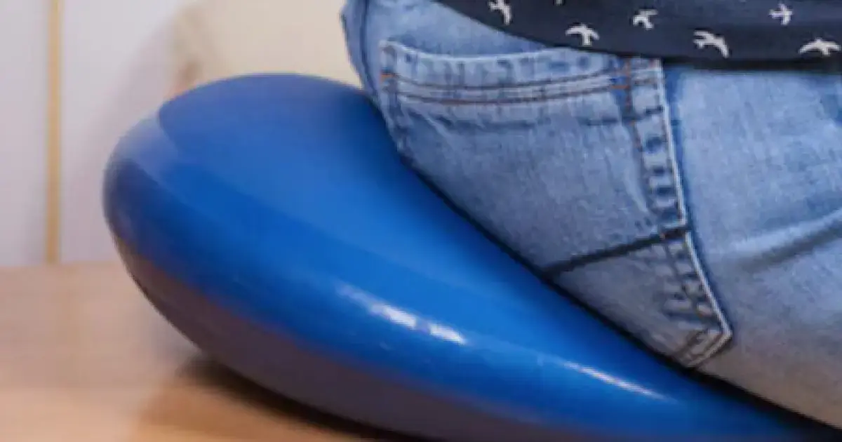 man with hemorrhoids sitting on a cushion