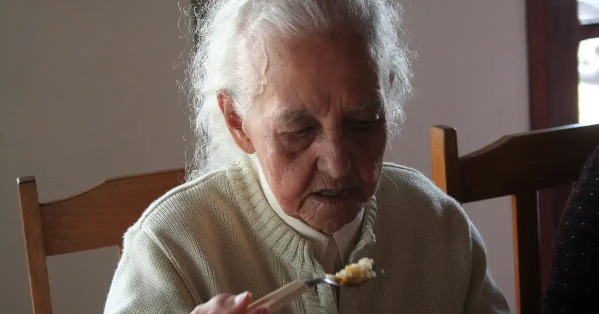 an elderly woman eating with a spoon