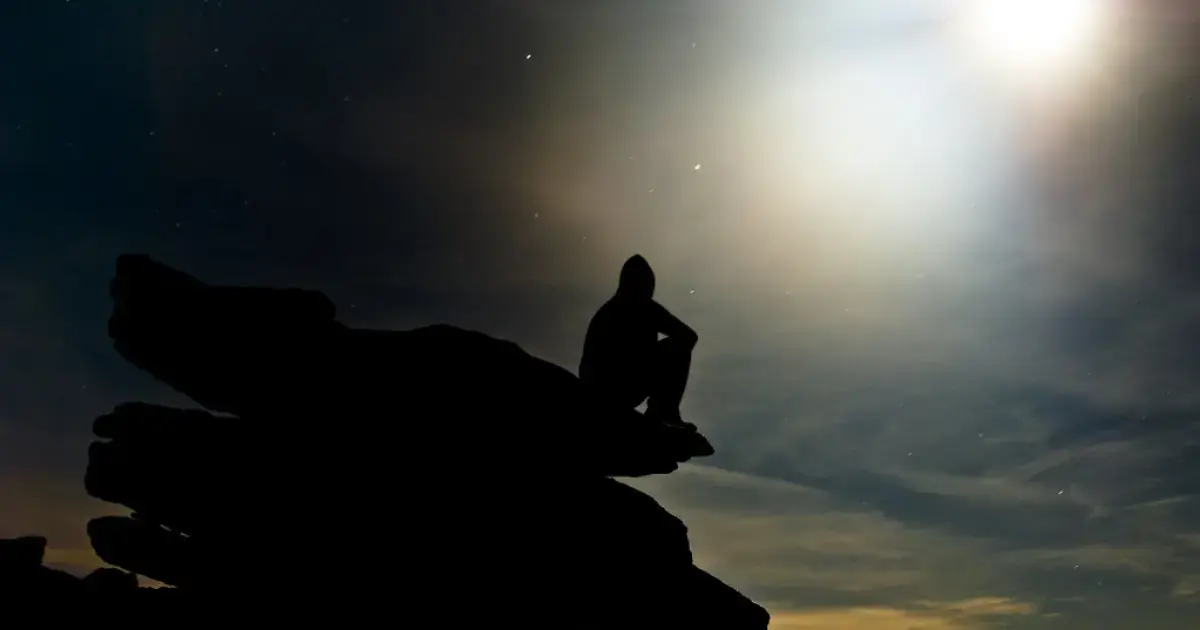 man sitting on a rock at night