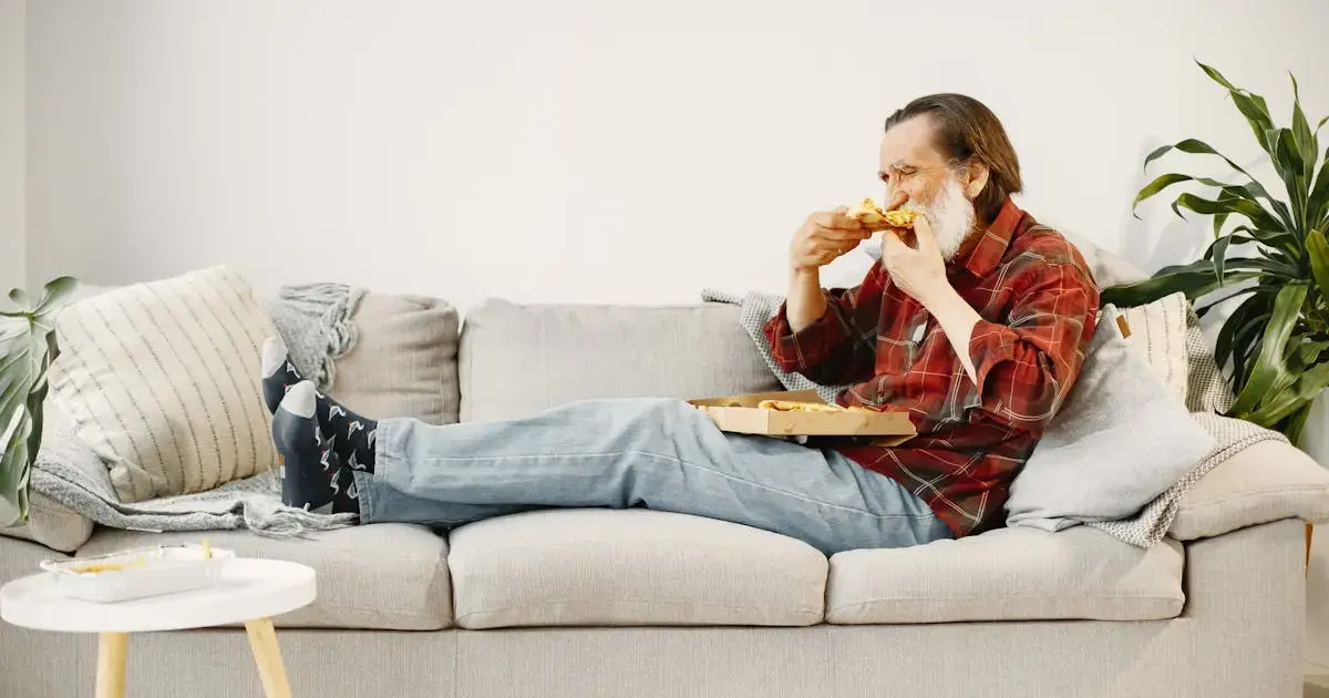 man eating pizza on the couch