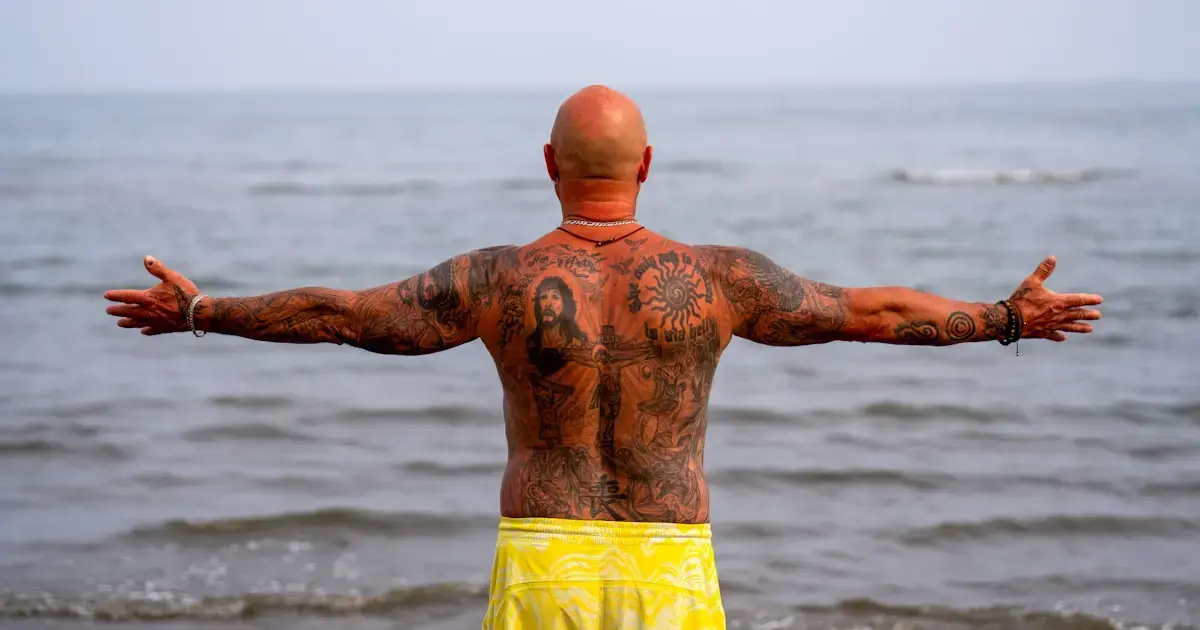 man with a tattoo on his back by the sea