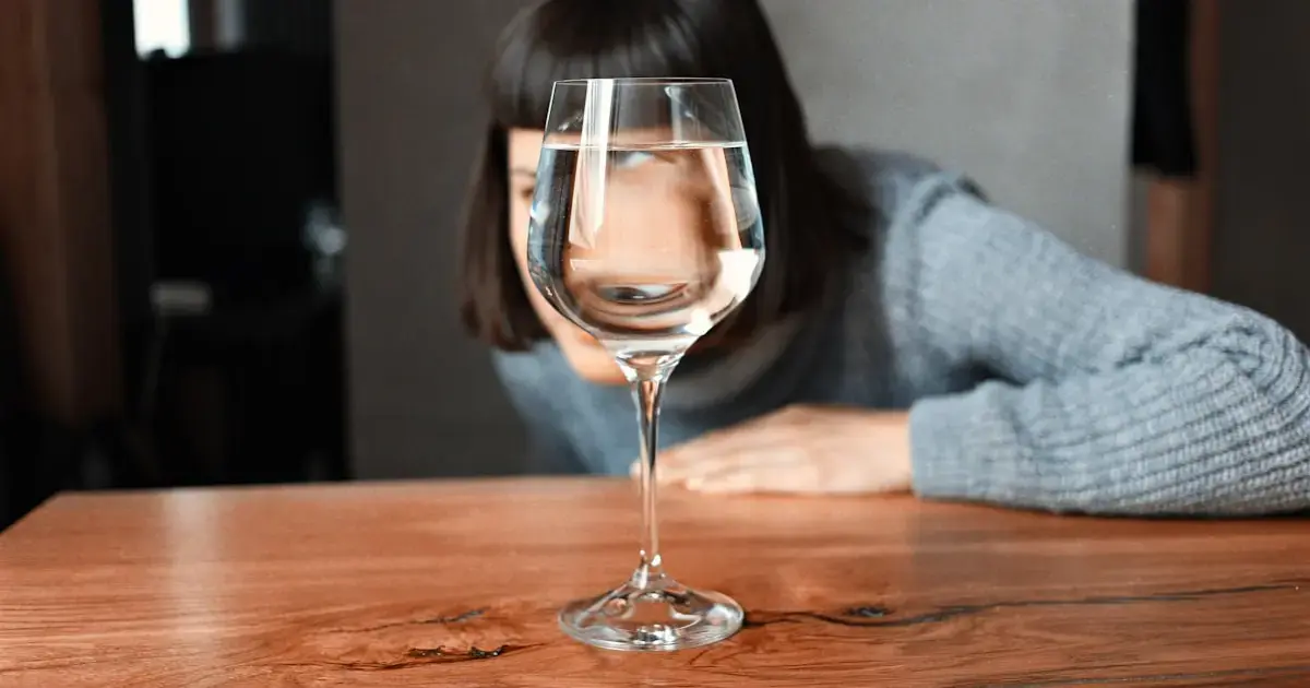 A woman hides her face behind a glass of wine