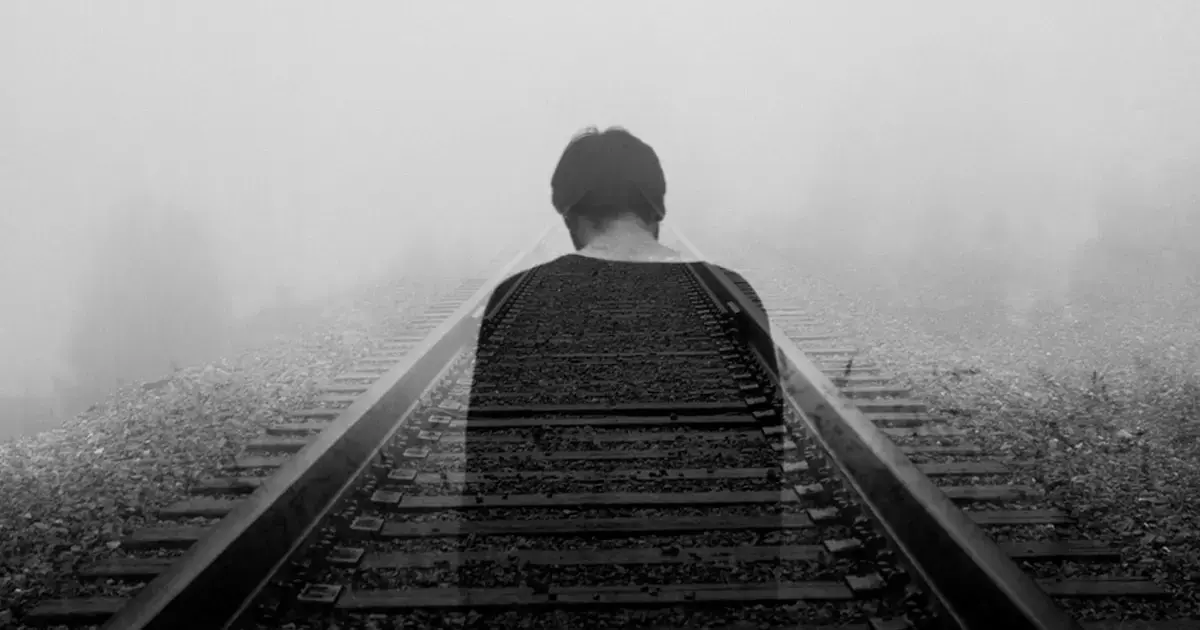 man walking on tracks in the fog