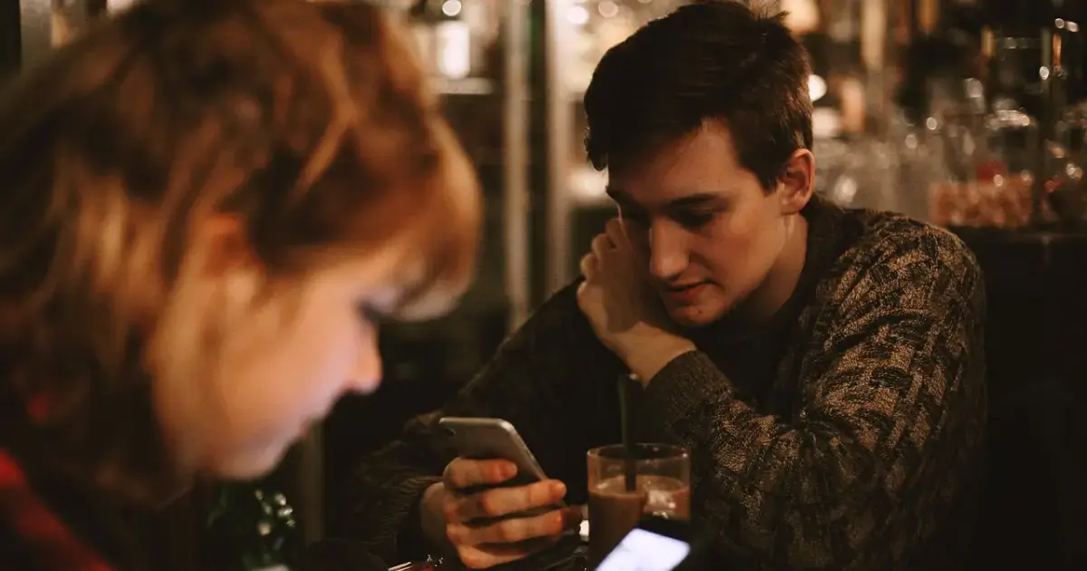a woman and a man in a café writing SMS